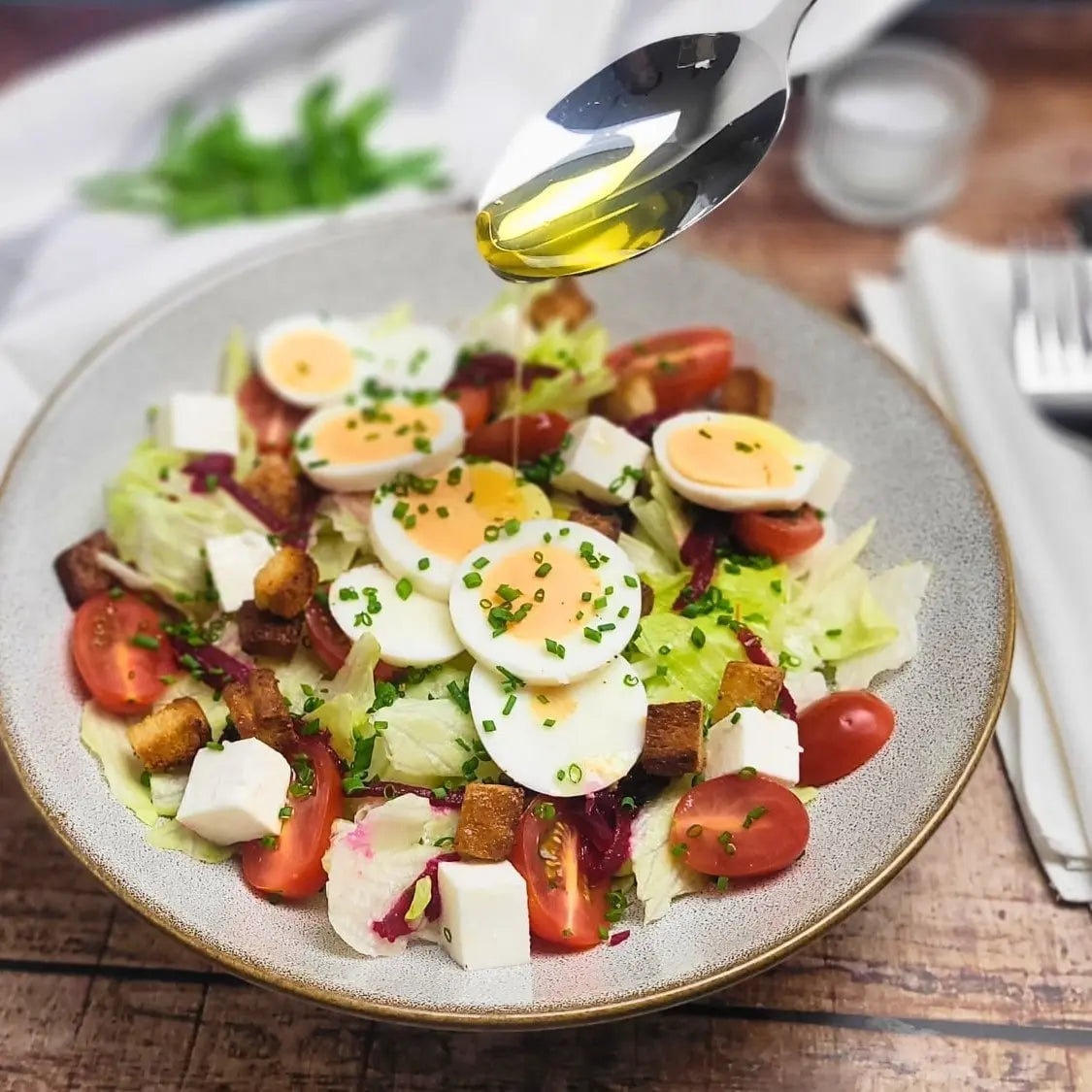 Frische Salatkomposition aus Eisbergsalat, Tomaten, Schafskäse und Ei, verfeinert mit edlem Haselnussöl