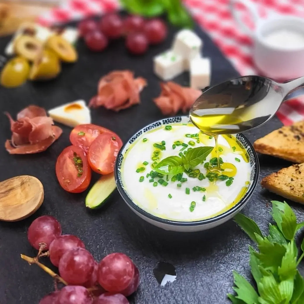 Herzhaft-mediterrane Picknickplatte mit frischen Tomaten, würzigen Oliven, Schinken und süßen Trauben